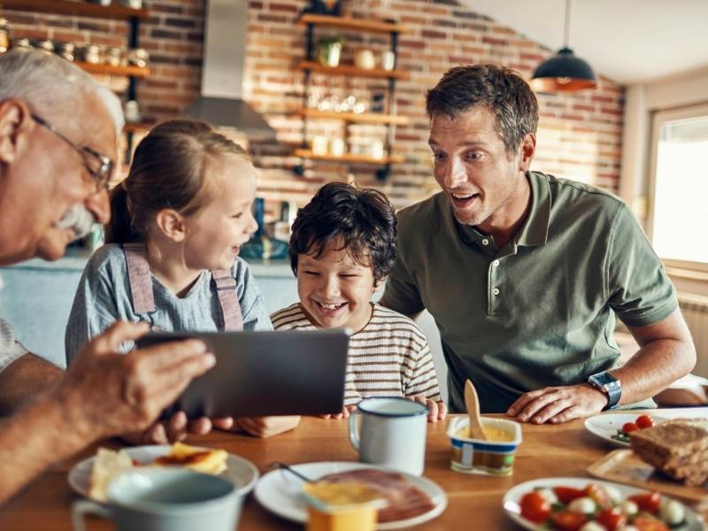 Father with his son and grandchildren watching something together on an tablet