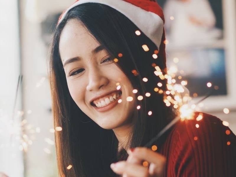 woman with a santa hat on and a sparkler